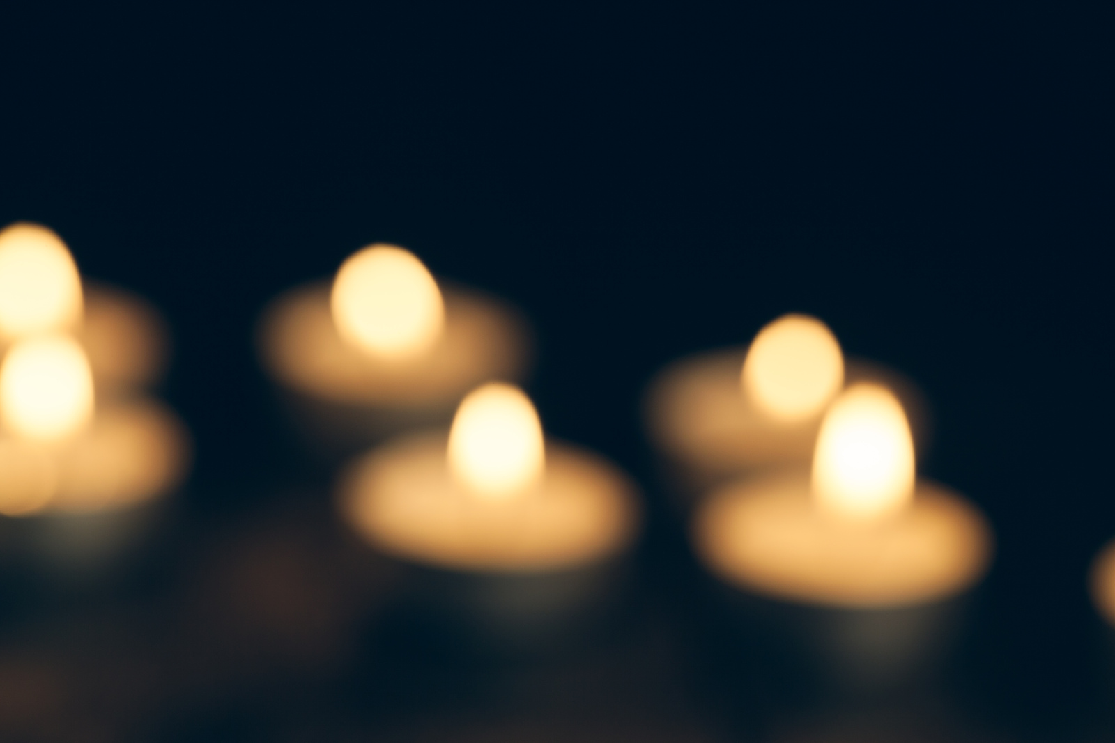 candles burning in darkness over black background. commemoration concept.